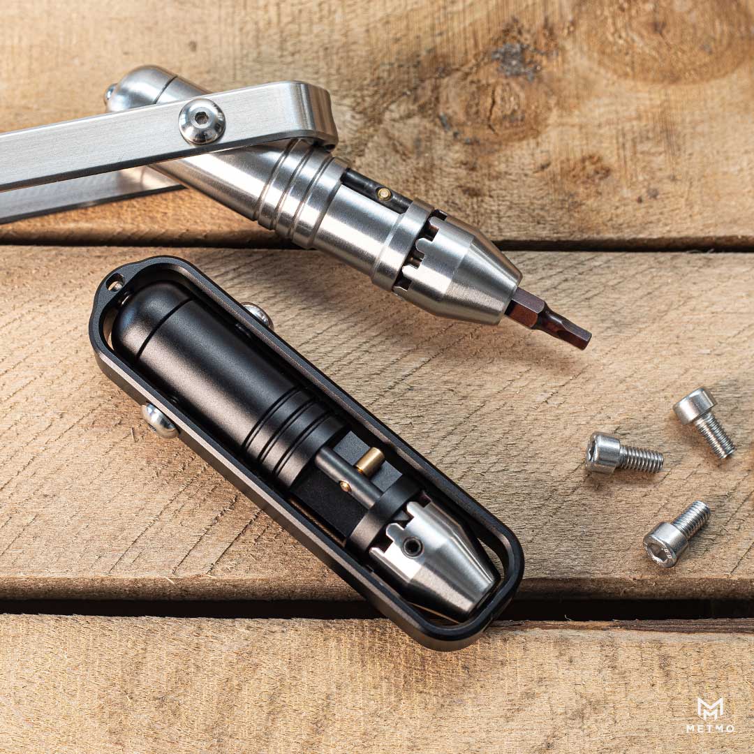 MetMo Pocket Driver in black and Steel, laying near screws