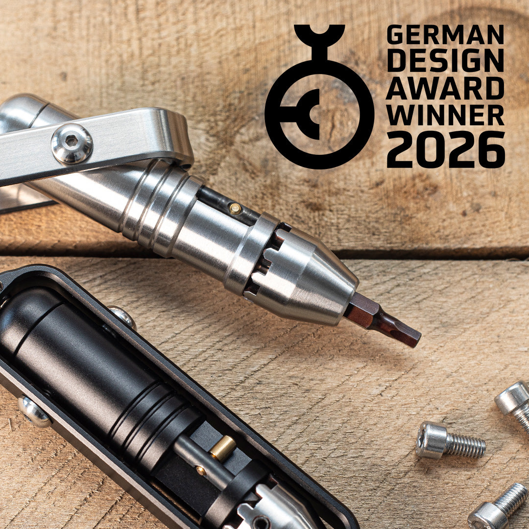 Metal Pocket Driver with interchangeable bits on a wooden surface, featuring the German Design Award 2026 logo.