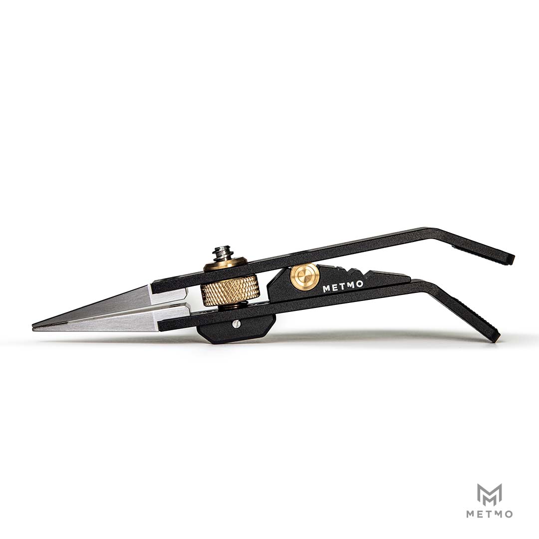 Black metal precision tweezers with silver stainless steel tips, gold-tone adjustment screws, and the brand name 'METMO' printed on the side, shown against a plain white background.