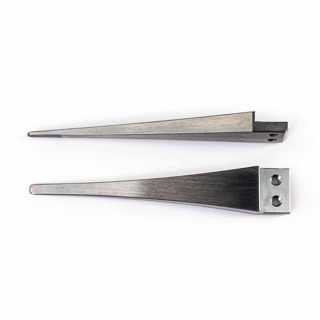 Two steel long wedge-shaped tool tips with different edge grooves and attachment holes, displayed side-by-side on a plain white background.