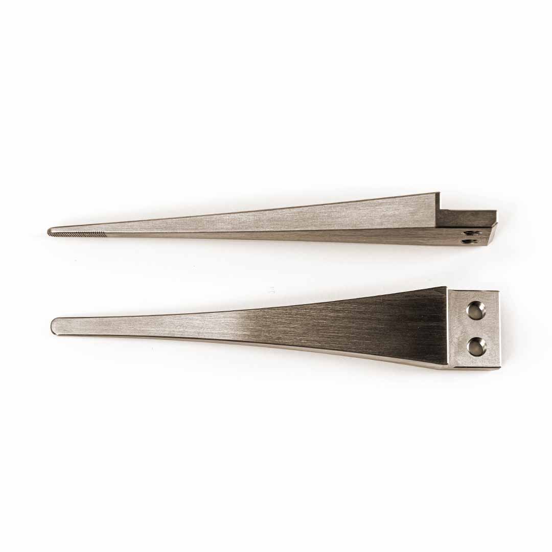 Two silver metal long wedge-shaped tool tips with different edge grooves and attachment holes, displayed side-by-side on a plain white background.