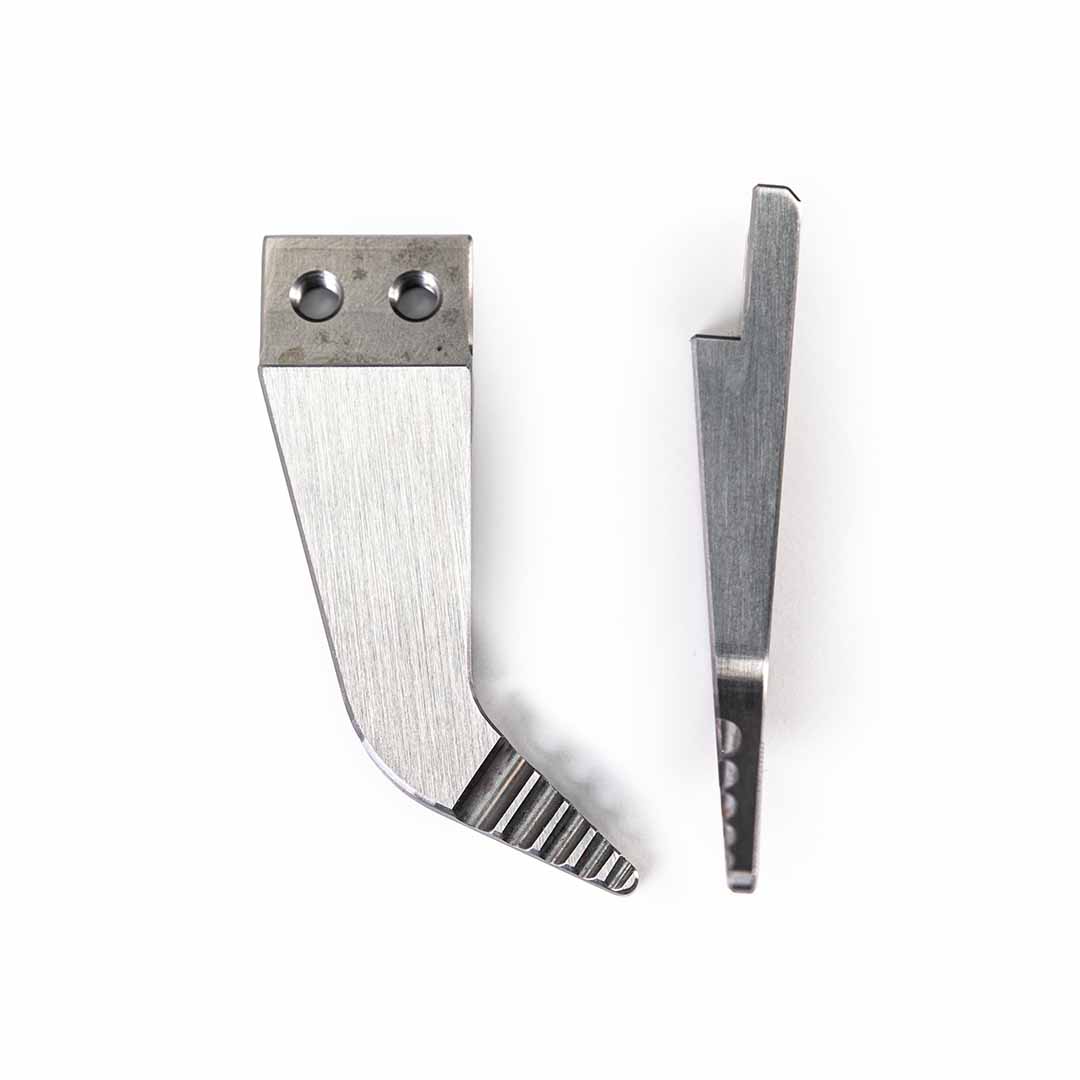 Two silver metal wedge-shaped tool tips with different edge grooves and attachment holes, displayed side-by-side on a plain white background.