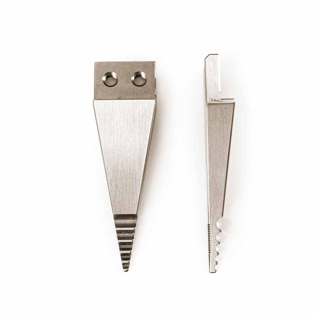 Two silver metal wedge-shaped tool tips with different edge grooves and attachment holes, displayed side-by-side on a plain white background.