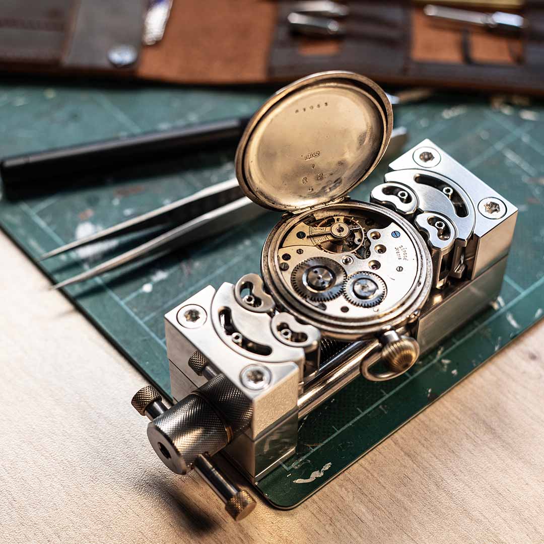 MetMo Stainless Steel Fractal Vise 82 holding a pocket watch for precision repair on a workbench