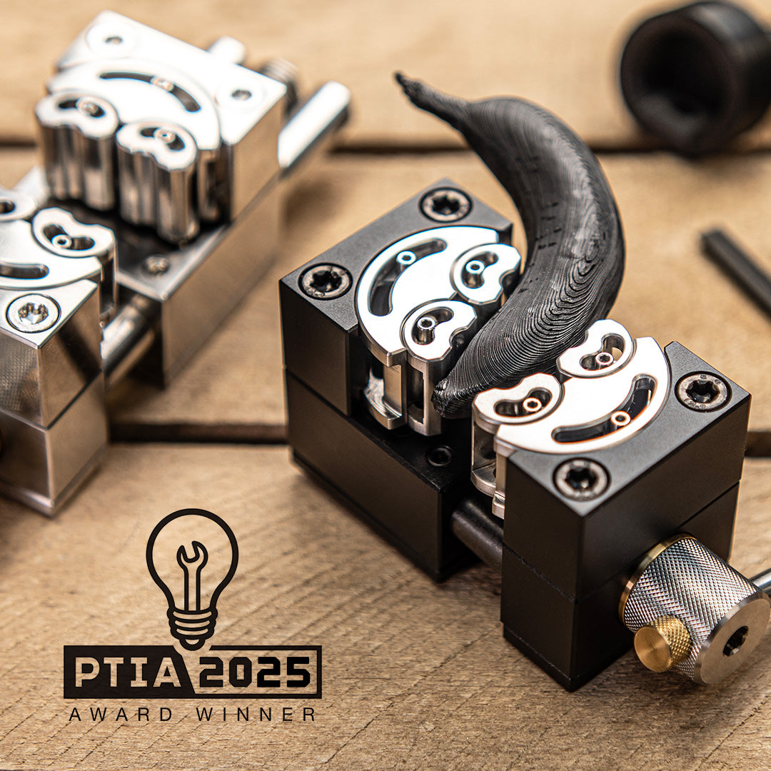 Close-up of MetMo Fractal Vise holding a small 3D printed banana on a wooden surface with PTIA 2025 Award Winner logo.