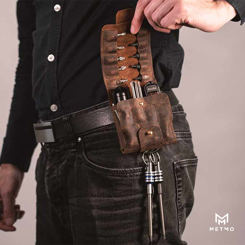 Brown leather tool pouch on a person's waist belt, open to show the tools inside, wearing black jeans and a dark shirt.