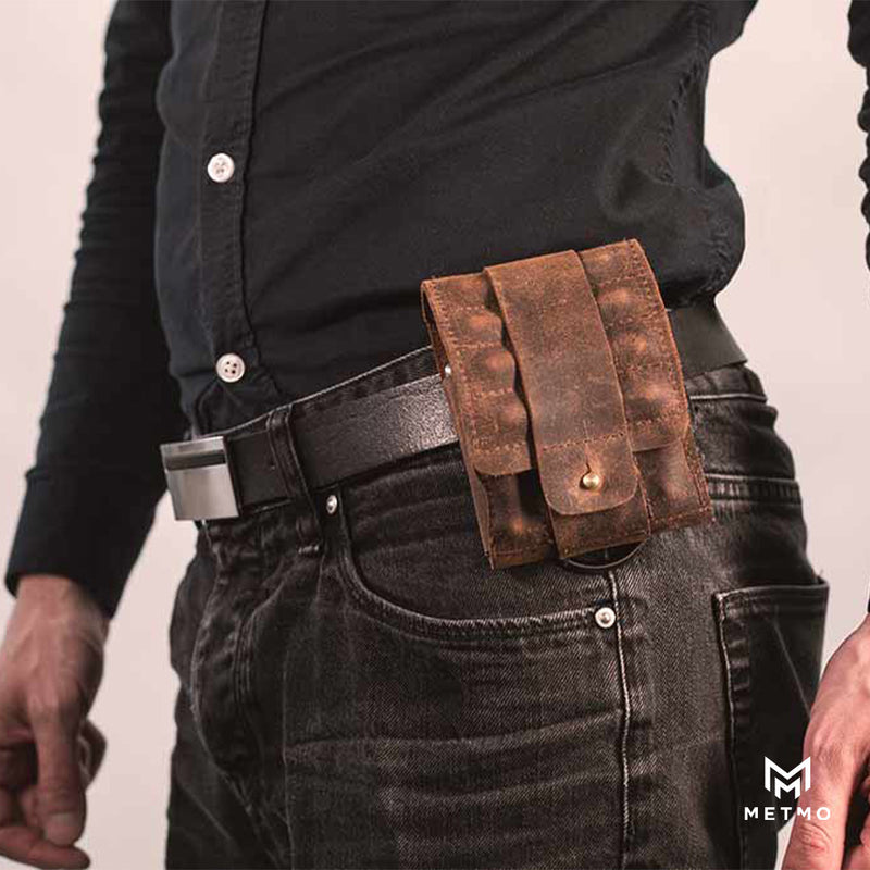 Brown leather pouch on a person's waist belt, wearing black jeans and a dark shirt.