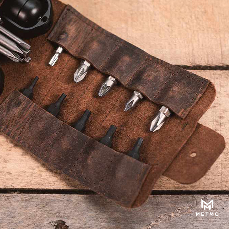 Set of drill bits in a brown leather holder on a wooden surface