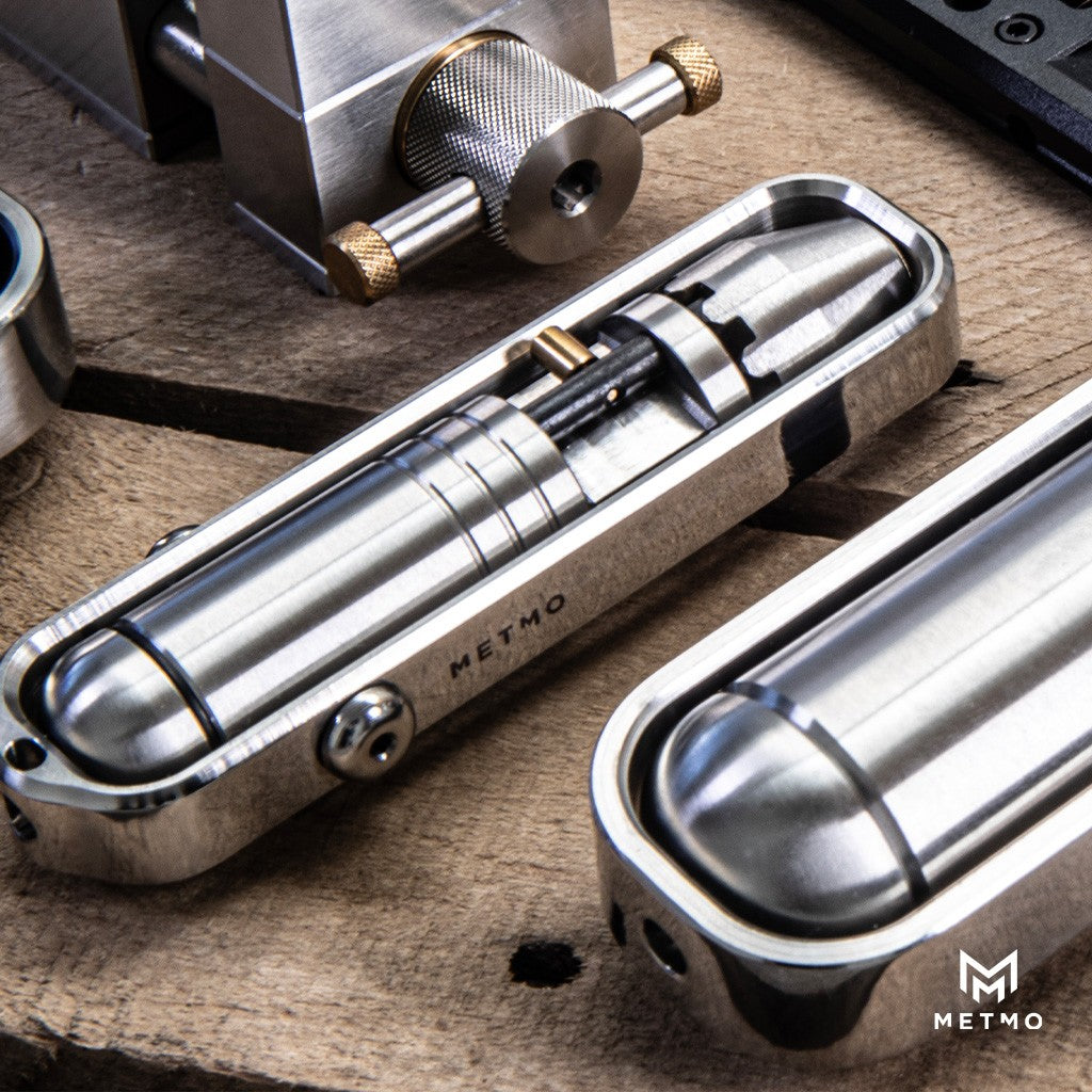 A collection of 3 Stainless steel toys on a bench with central product being the pocket driver 