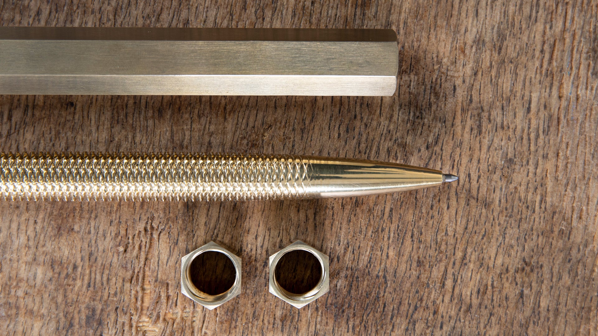 MetMo brass pen with two nuts on a wooden surface