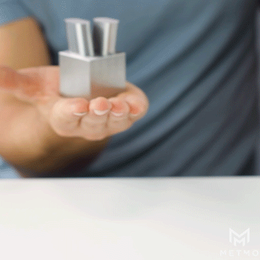 MetMo Cube in the palm of a hand with metals pins dropping inside 