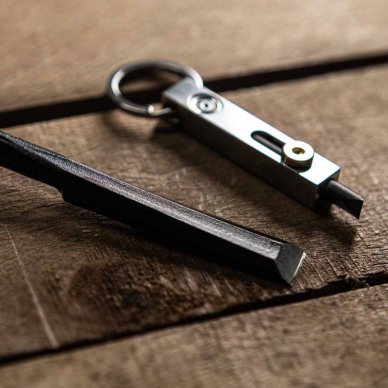 Silver MetMo Edge next to a chisel on a wooden surface