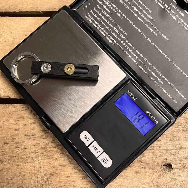 Digital pocket scale weighing a MetMo Edge on a wooden surface