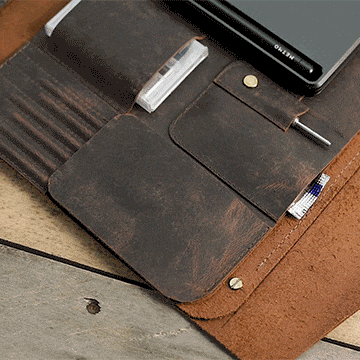 Person opening a protective leather flap inside the MetMo Multi Drive Expansion Kit and removing a metal file from a secure storage compartment in the kit.