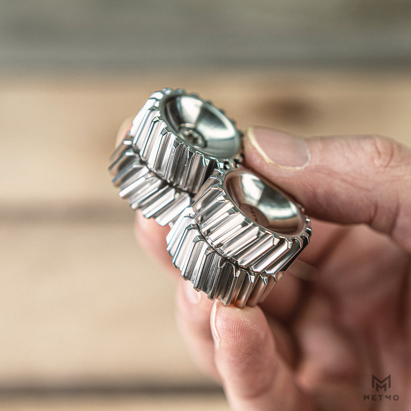 Close-up of a hand holding a metallic helico gear against a blurred background