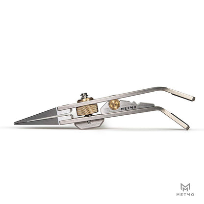 A METMO precision tweezer tool with titanium jaws and brass adjustment knobs, shown on a clean white background.