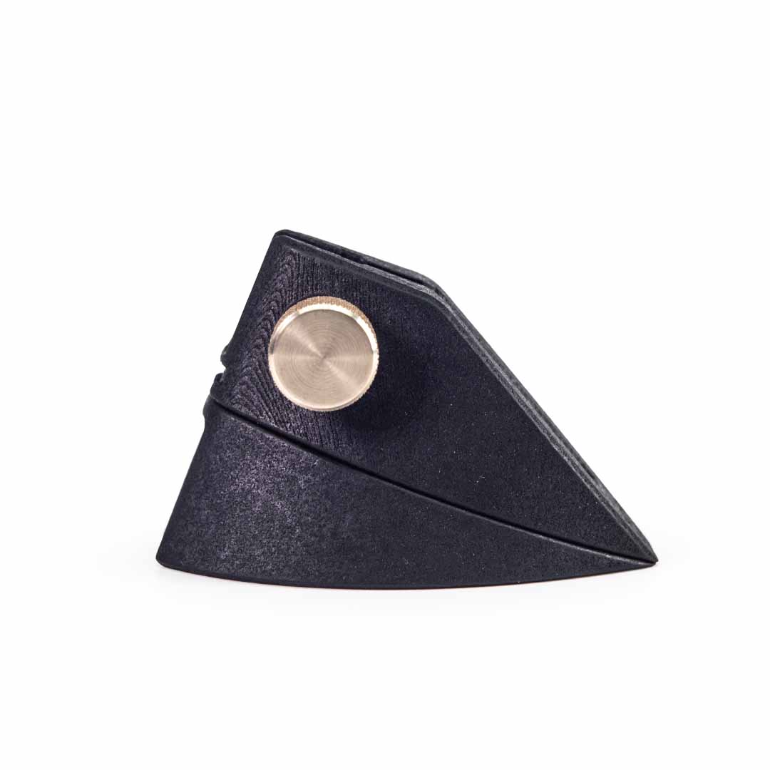 A black textured 3D printed wedge-shaped accessory stand with a round metallic brass turner, shown on a plain white background.