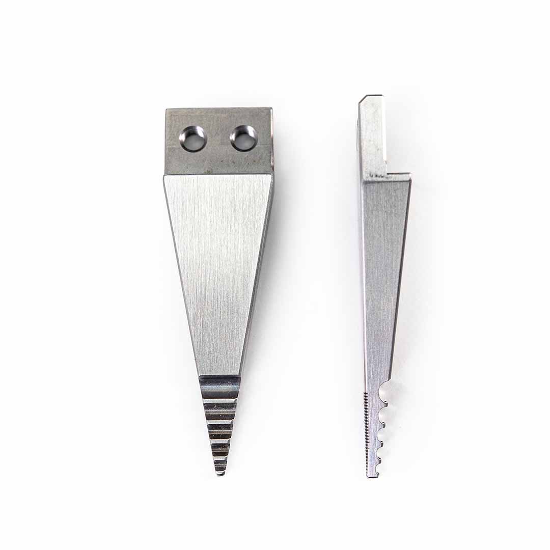 Two silver metal wedge-shaped tool tips with different edge grooves and attachment holes, displayed side-by-side on a plain white background.