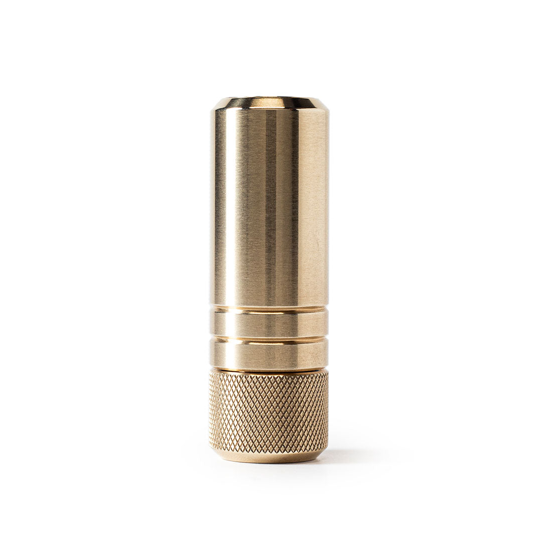 MetMo Piston precision brass fidget toy in vertical view on white background with retracted piston