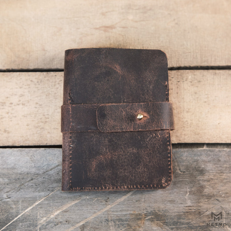 Brown leather tool roll on a wooden surface