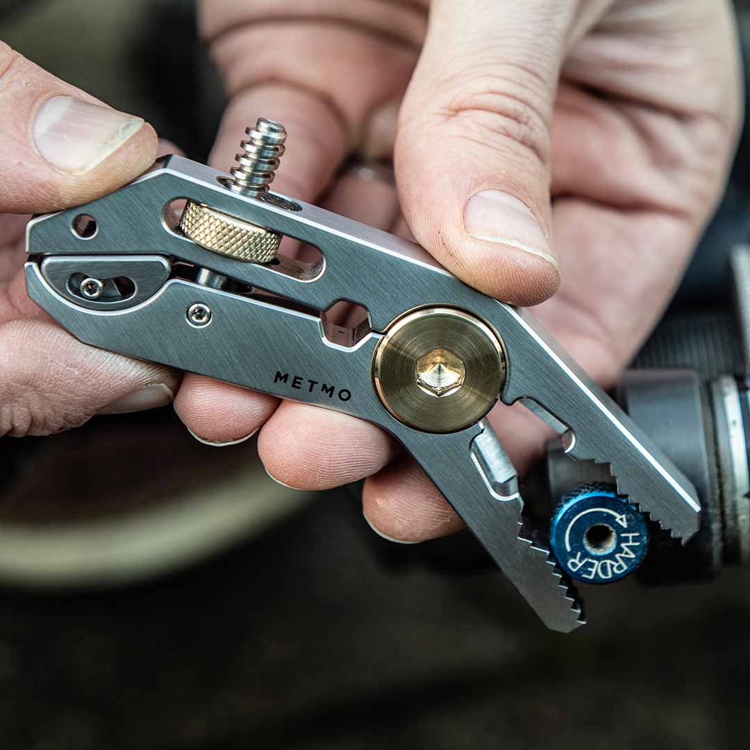 Close-up of a steel multi-tool with various components held by hands.