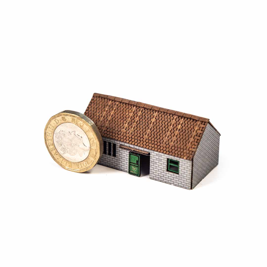 Model of a shed next to a British pound coin on a white background