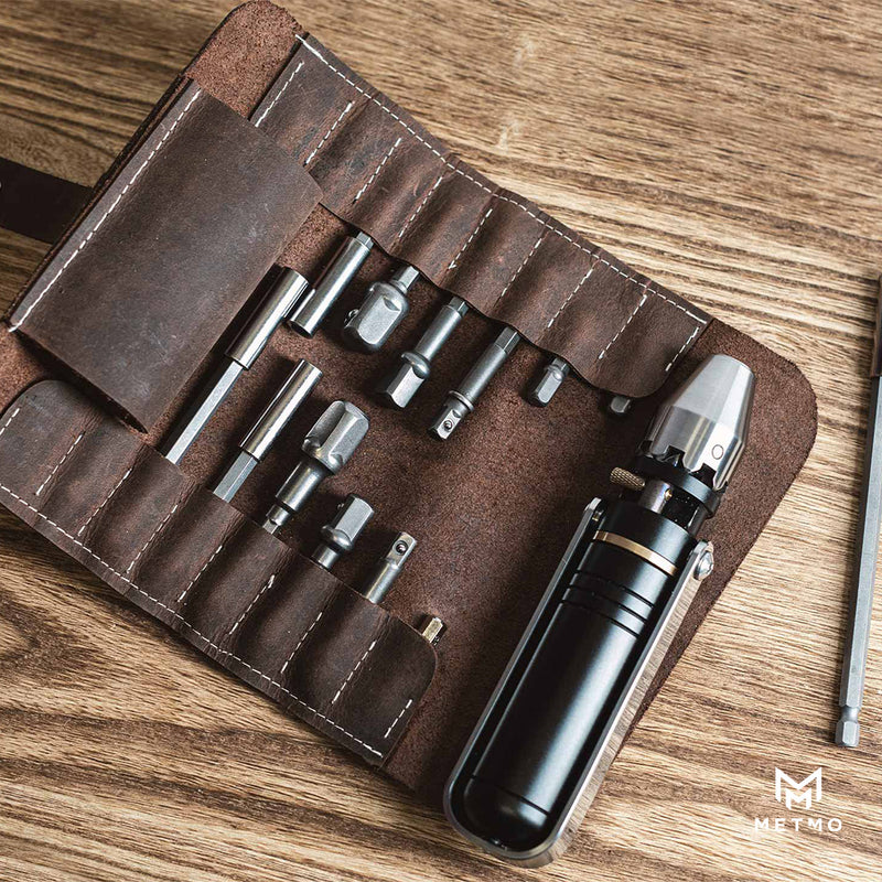 MetMo Driver and  different sized bits and shanks in a brown leather case on a wooden surface
