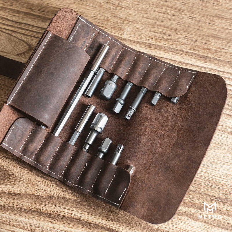 Different sized bits and shanks in a brown leather case on a wooden surface