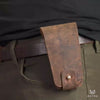 Leather tool pouch attached to a brown belt being worn. Pouch is opened and tool removed. 
