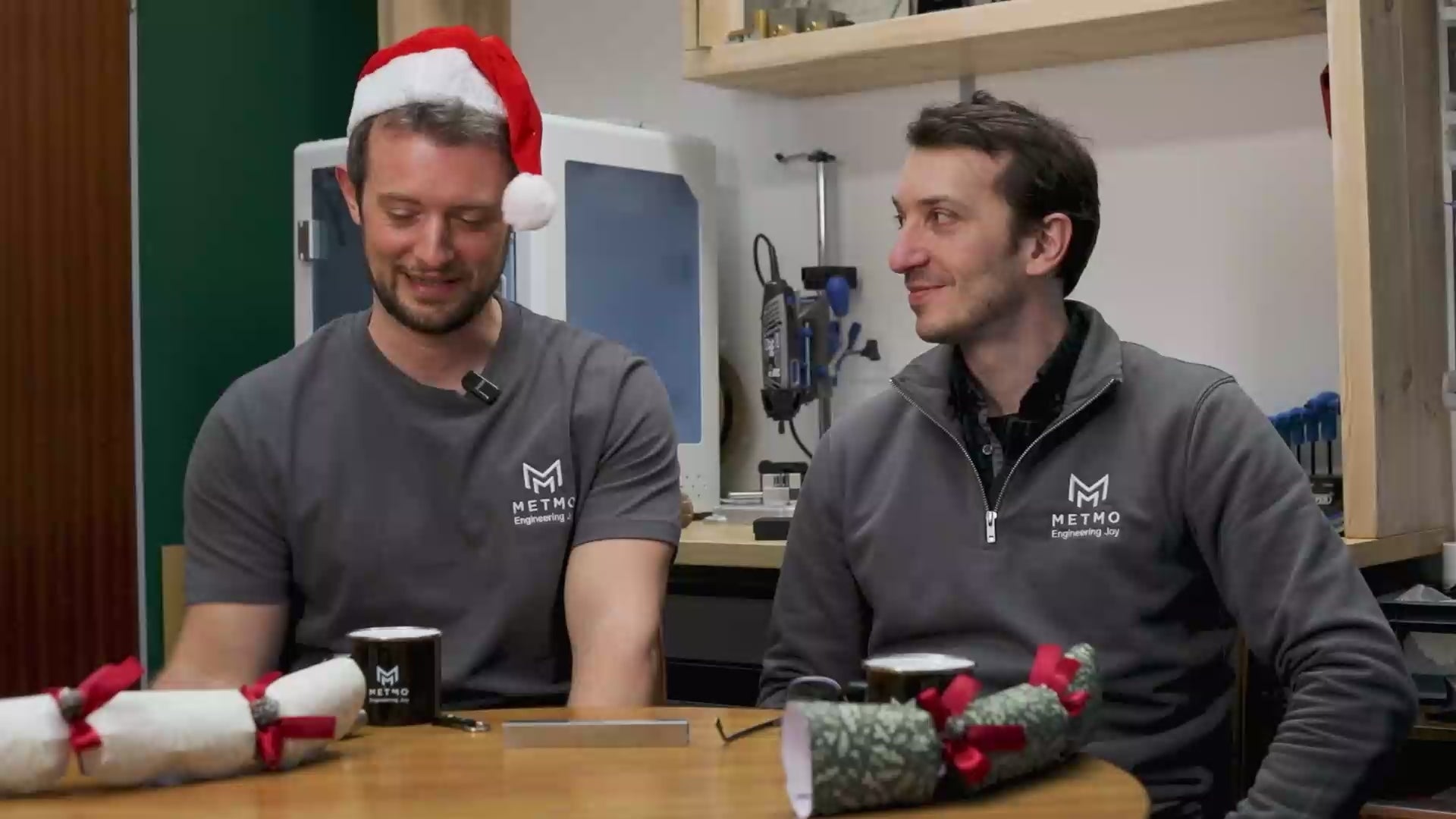 Load video: MetMo founders James and Sean sat in their office. Sean is wearing a Christmas Santa hat. They pull a Christmas cracker unsuccessfully, and reattempt while laughing.