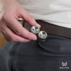 A hand puts a silver helico into the pocket of a pair of black trousers