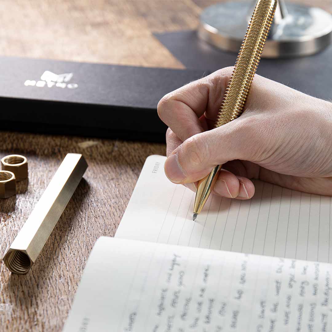 MetMo Brass Pen writing notes at a desk